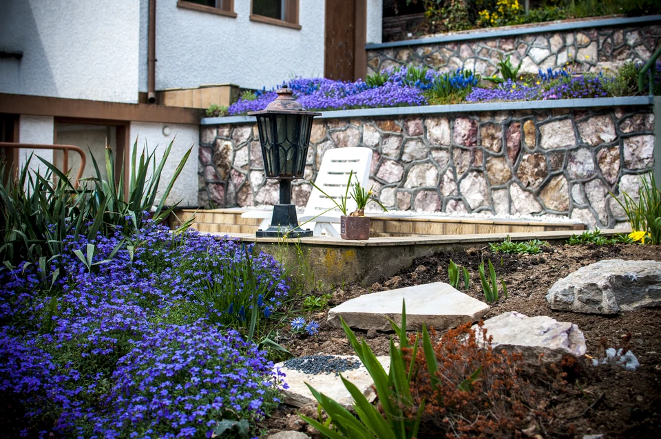 Terrassierter Garten mit Natursteinmauern und blühender Bepflanzung